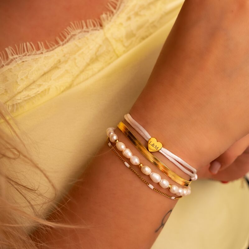 Model draagt mix van gouden en witte armbanden