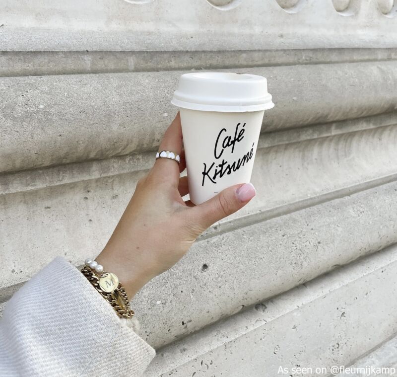 influencer draagt finaste sieraden en houdt koffie vast