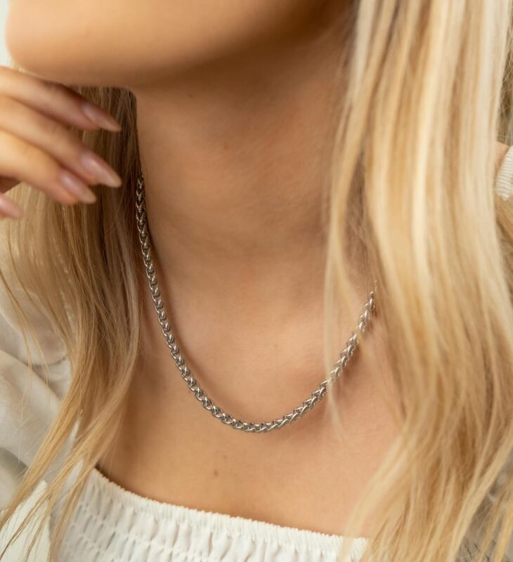 Het model draagt de zilverkleurige ketting met gevlochten chains