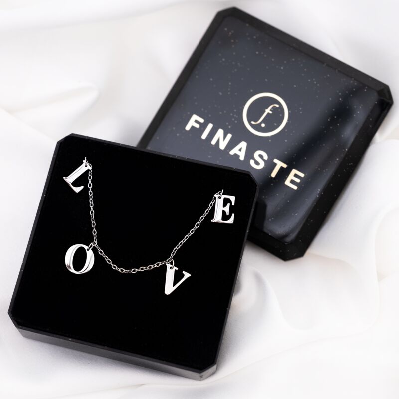 Zilveren letter ketting love om de hals bij een vrouw met blonde haren