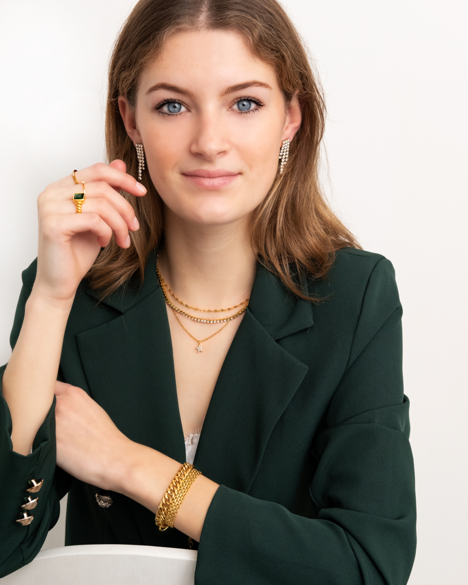gouden sieraden op vrouw met groene blazer