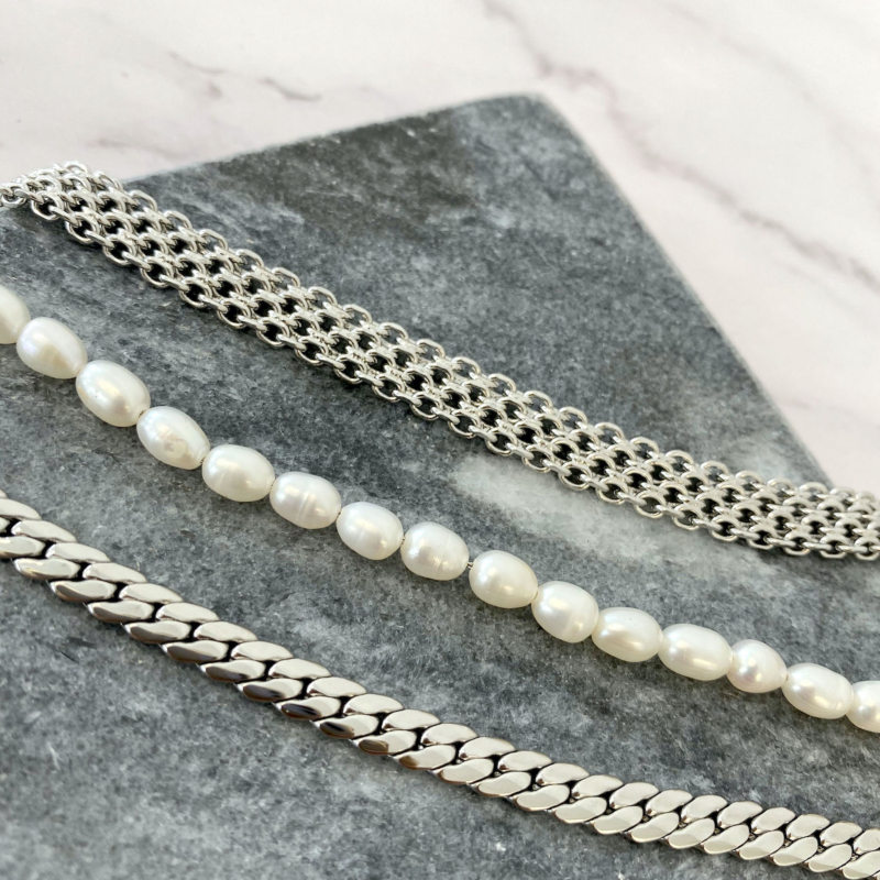 Mooie mix van zilverkleurige armbanden op een stenen achtergrond