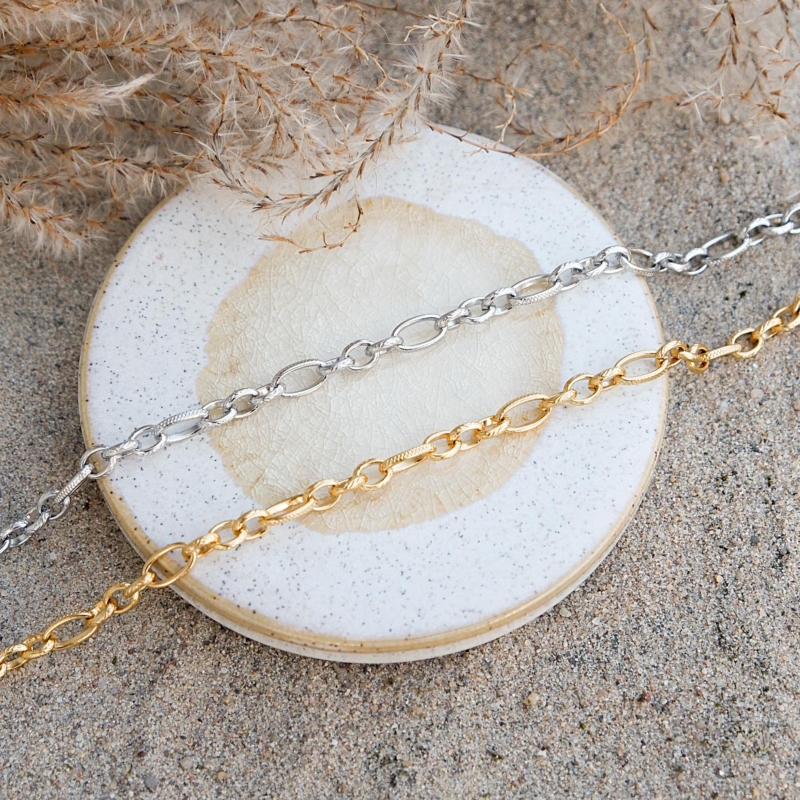 Gouden en zilveren enkelbandjes in het zand