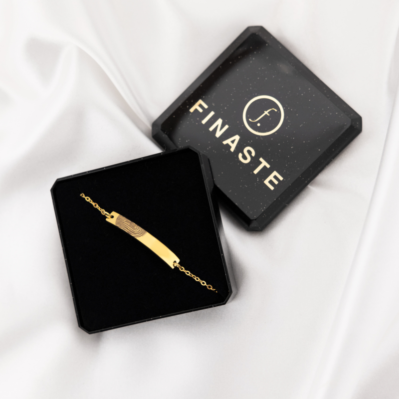graveerbare gouden bar armband met vingerafdruk in doosje op satijnen achtergrond