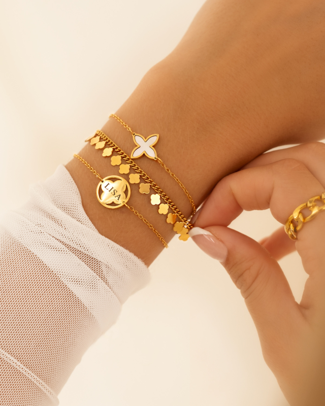 Model draagt gouden clover armbaden mix