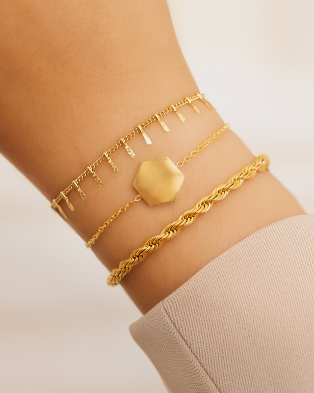 Model draagt gouden bedelarmbanden