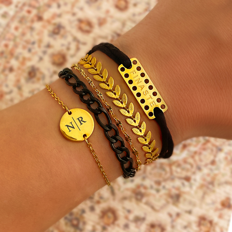 Vrouw draagt mix van zwarte en gouden armbanden