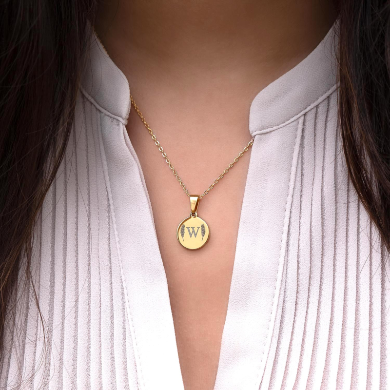 Gouden ketting met letter bij een roze top