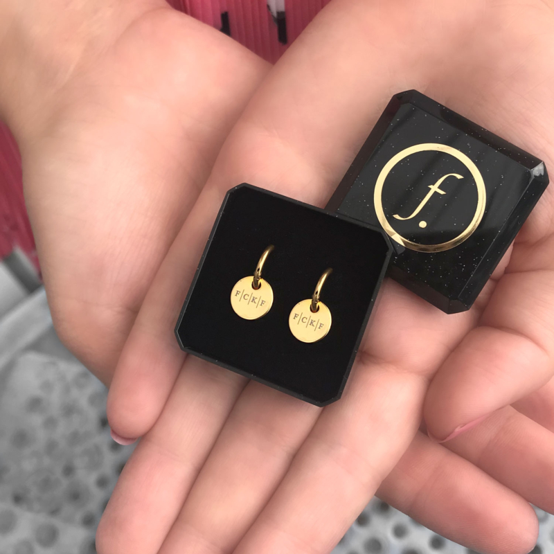 Gouden oorringetjes in een sieradendoosje met vier initialen