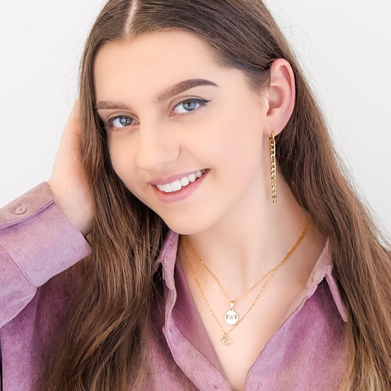 Vrouw draagt gouden ketting met gravering om de hals