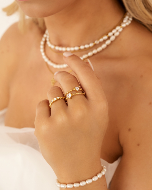 Mix van gouden ringen en parelarmband