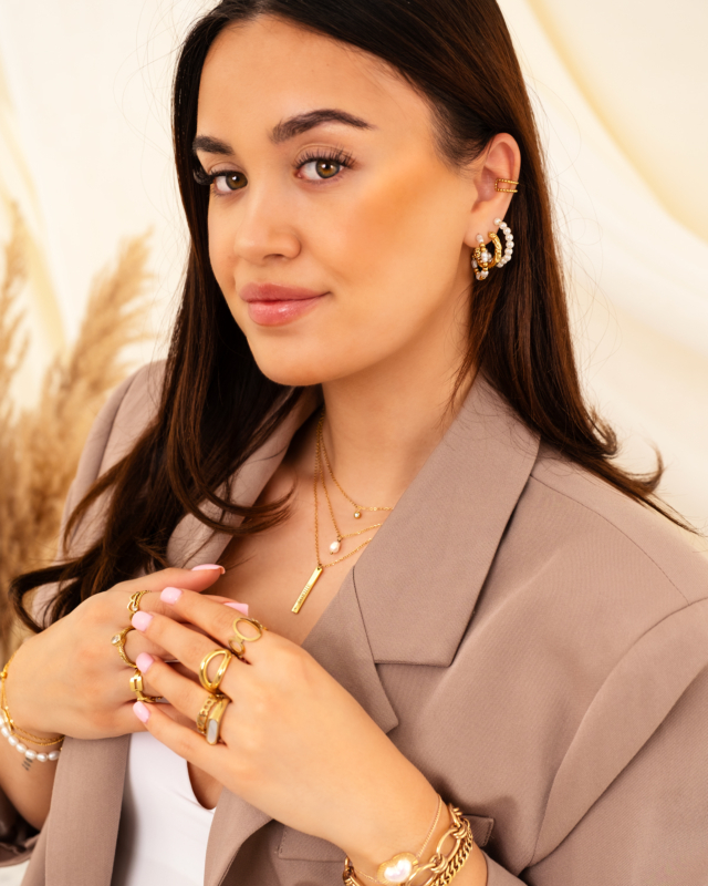 Model draagt gouden sieraden mix met parels