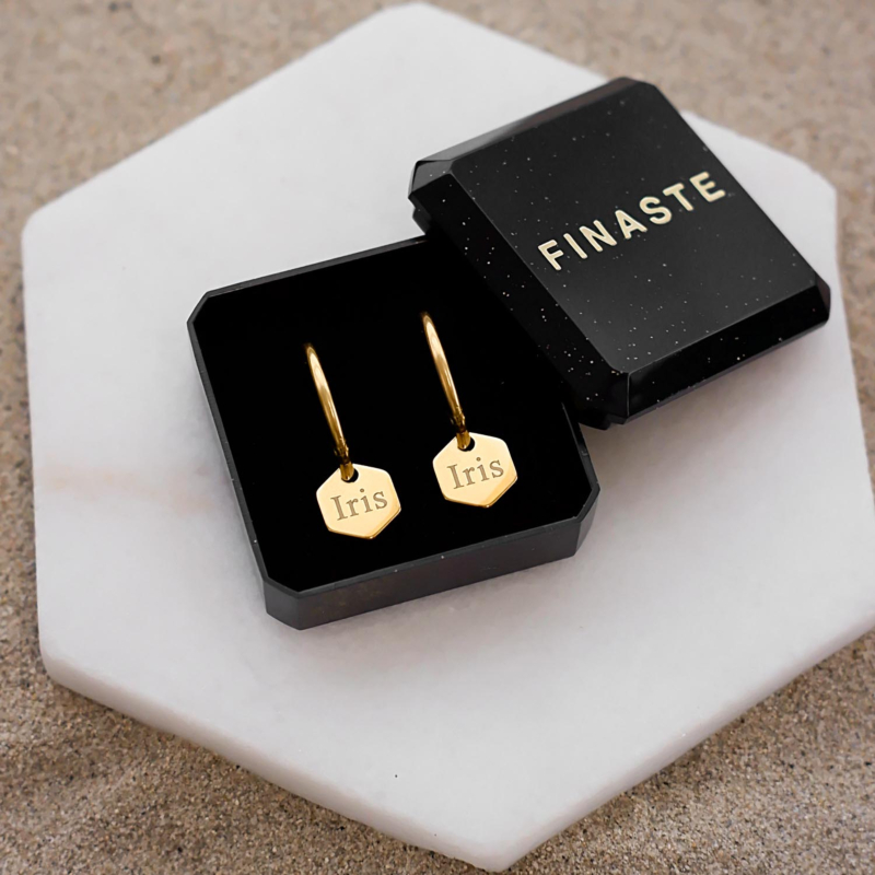 Goudkleurige oorbellen in een sieradendoosje met naam