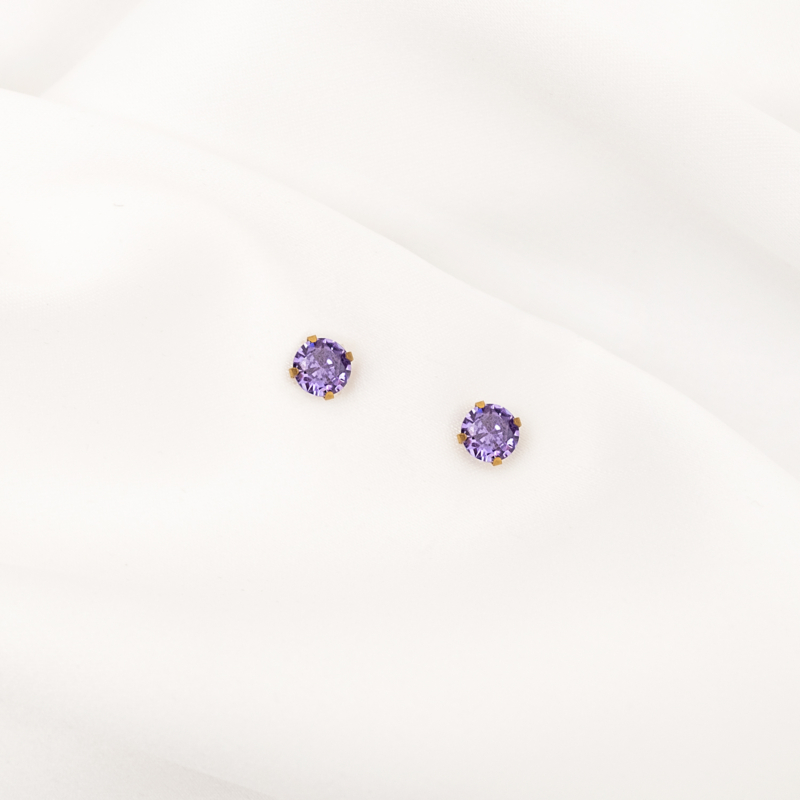 Mooie gouden oorknopjes met paars steentje op wit satijn