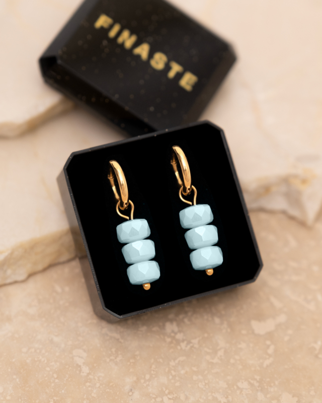 Gouden oorringetjes met blauwe steentjes in sieradendoosje