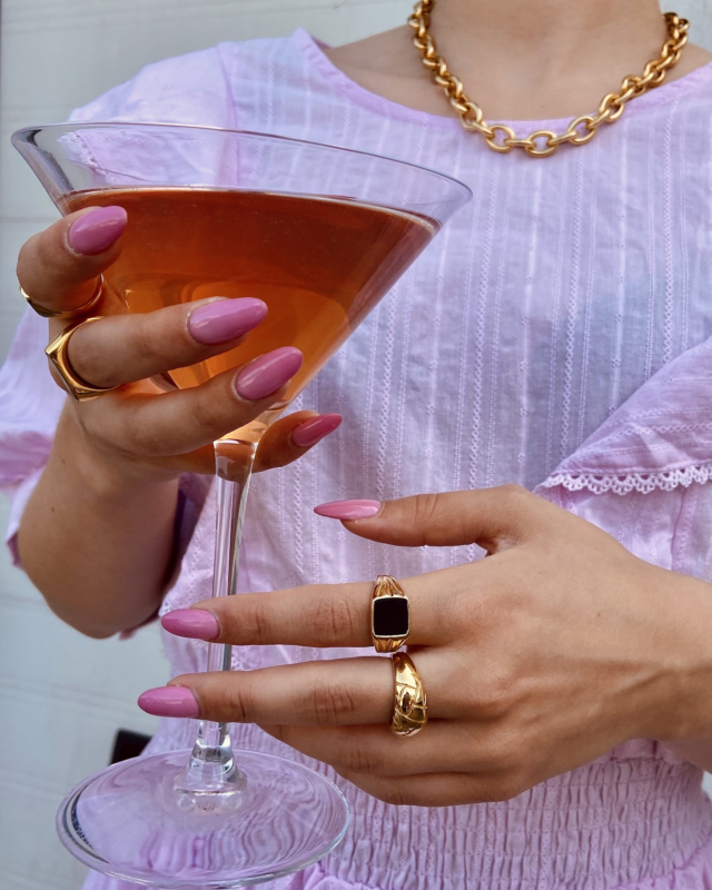 Trendy chunky ringen om de hand van het model met een cocktail in haar hand