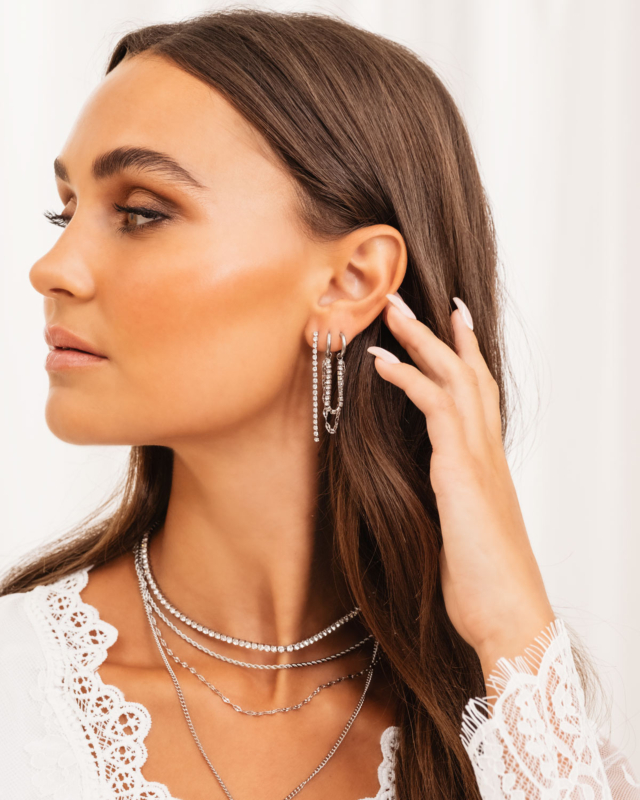 Model draagt mooie zilveren oorbellen en kettingen
