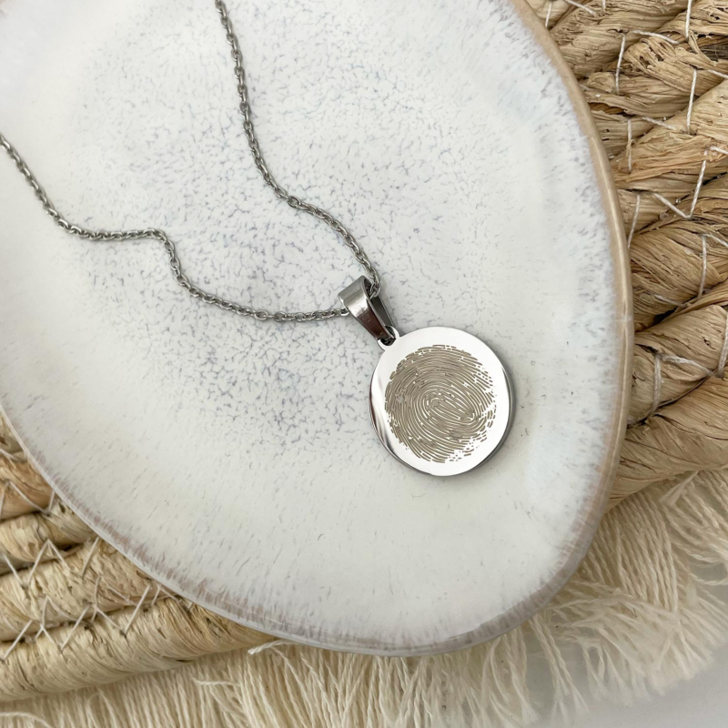Zilveren vingerafdruk ketting op stenen ondergrond
