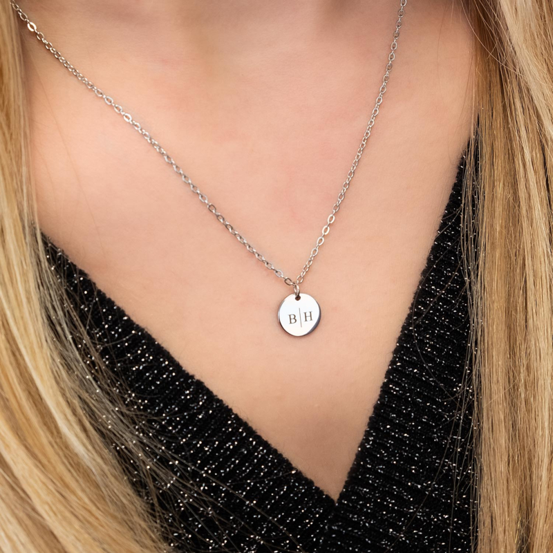 Vrouw draagt zilveren initialen ketting om bij