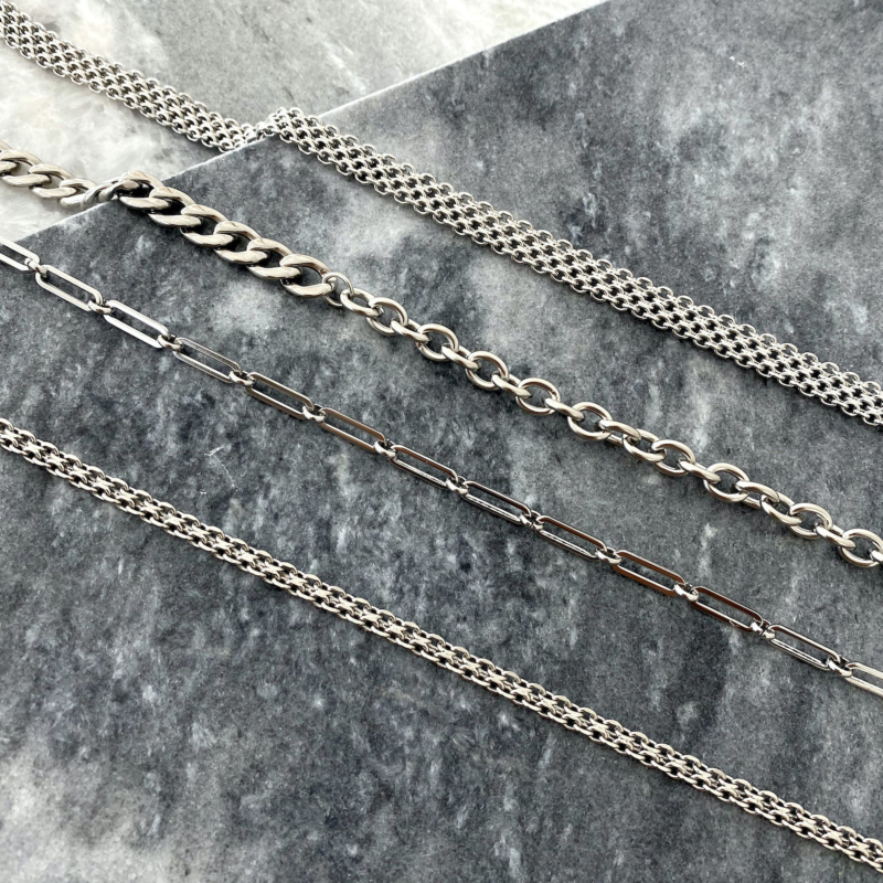 Mix van verschillende zilverkleurige kettingen op een stenen achtergrond