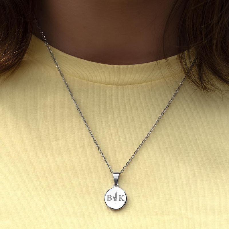 Zilveren ketting met twee initialen om de hals bij gele top
