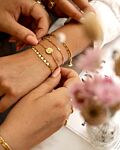 Model draagt gouden armbanden
