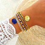 Model draagt gouden armbanden met blauwe details