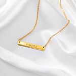 Mooie gouden bar ketting met gravering op satijn