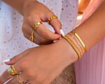 Vrouw draagt gouden sieradenlook met armbanden en ringen