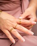 gouden ringen om vingers van vrouw met roze jurk