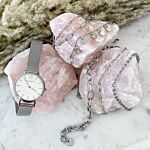 Zilveren armbandjes en horloge bij roze stenen