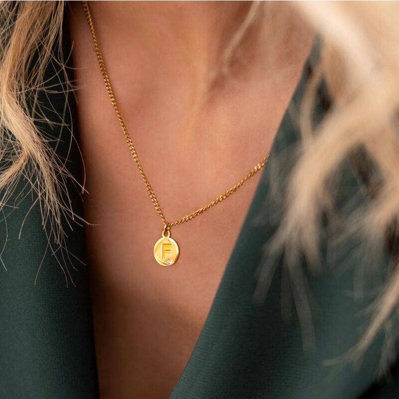 gouden ketting met initial en shiny steentje om nek