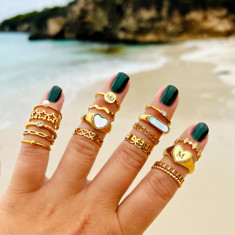 Hand met verschillende gouden ringen op strand 