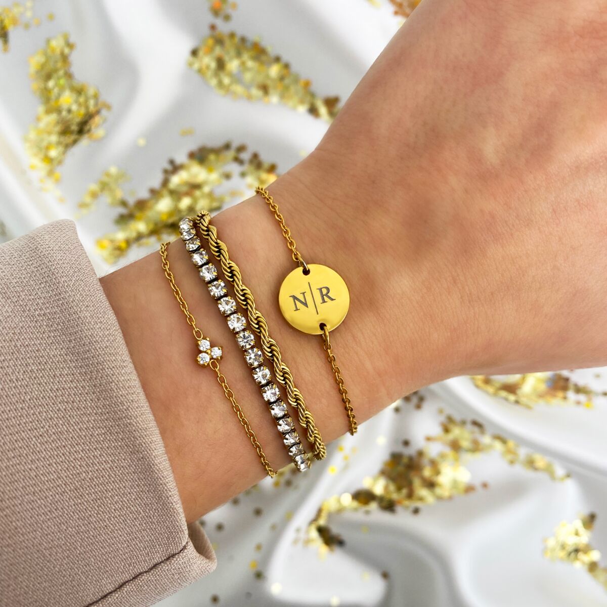 gouden armbanden met stenen details om pols met glitter achtergrond