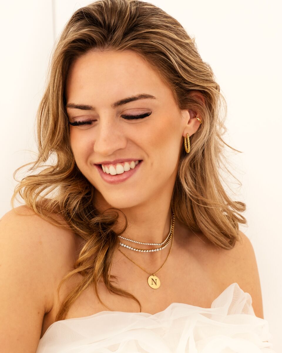 Model draagt mix van gouden kettingen en oorbellen