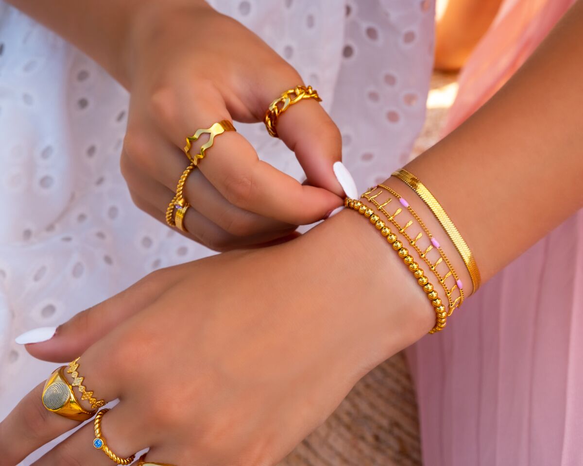 Vrouw draagt gouden sieradenlook met armbanden en ringen