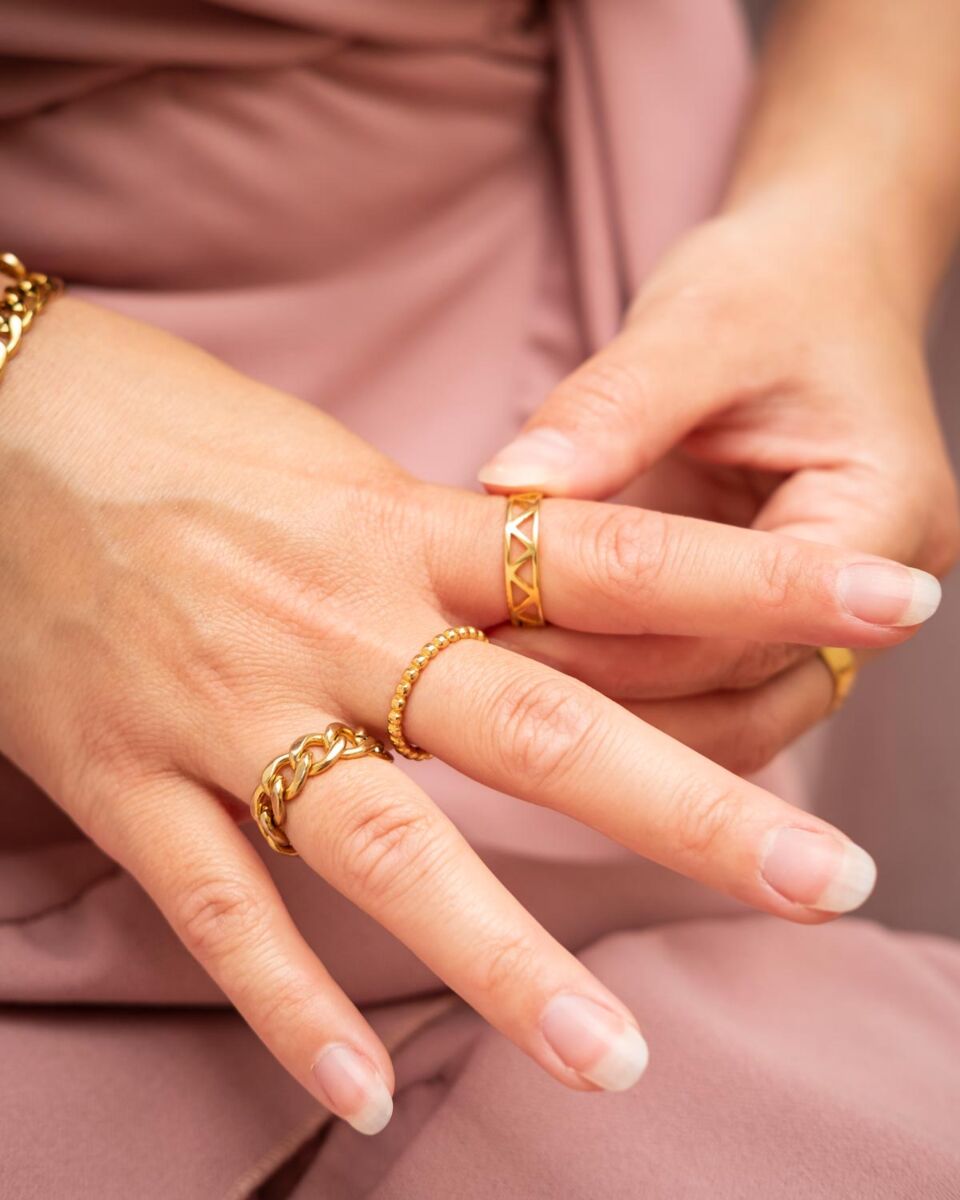 gouden ringen om vingers van vrouw met roze jurk