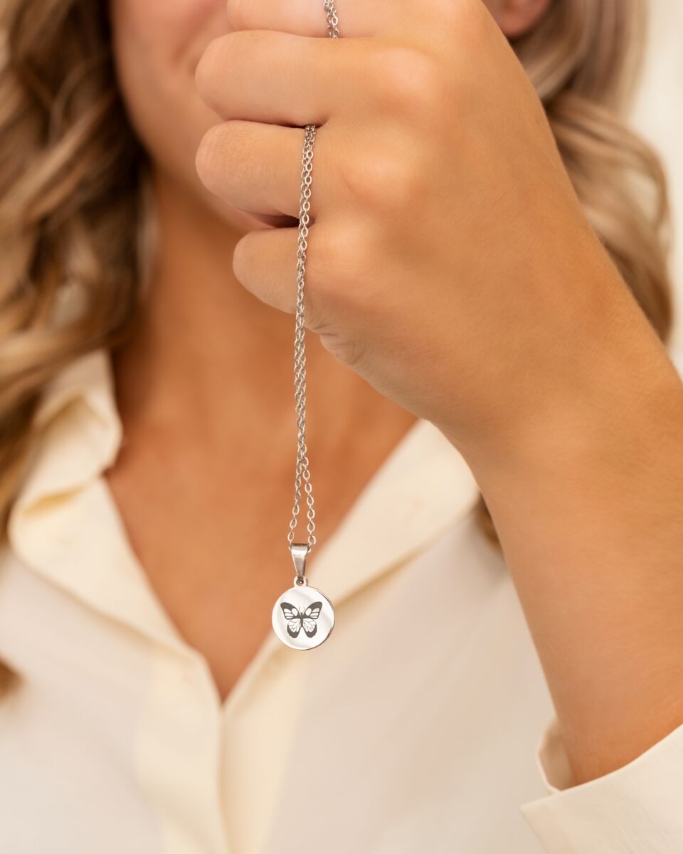 Model houdt Birth month butterfly ketting vast