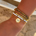 Pols met mix van mooie gouden armbanden op strand