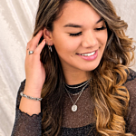 Meisje draagt ketting met parelmoer en twee initialen om hals