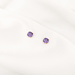 Mooie gouden oorknopjes met paars steentje op wit satijn