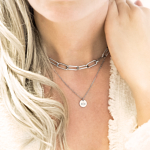 Vrouw draagt zilveren schakelketting samen met initialen