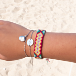 Zilveren initial armband met gekleurde armbandjes om de pols