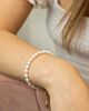 Het model draagt de goudkleurige musthave parel armband om haar pols