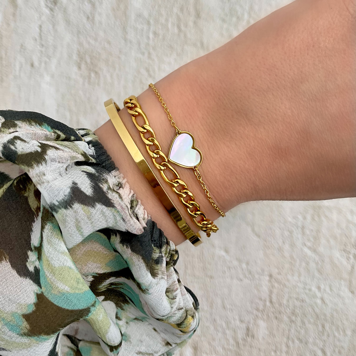 gouden armparty met parelmoer hartje om pols